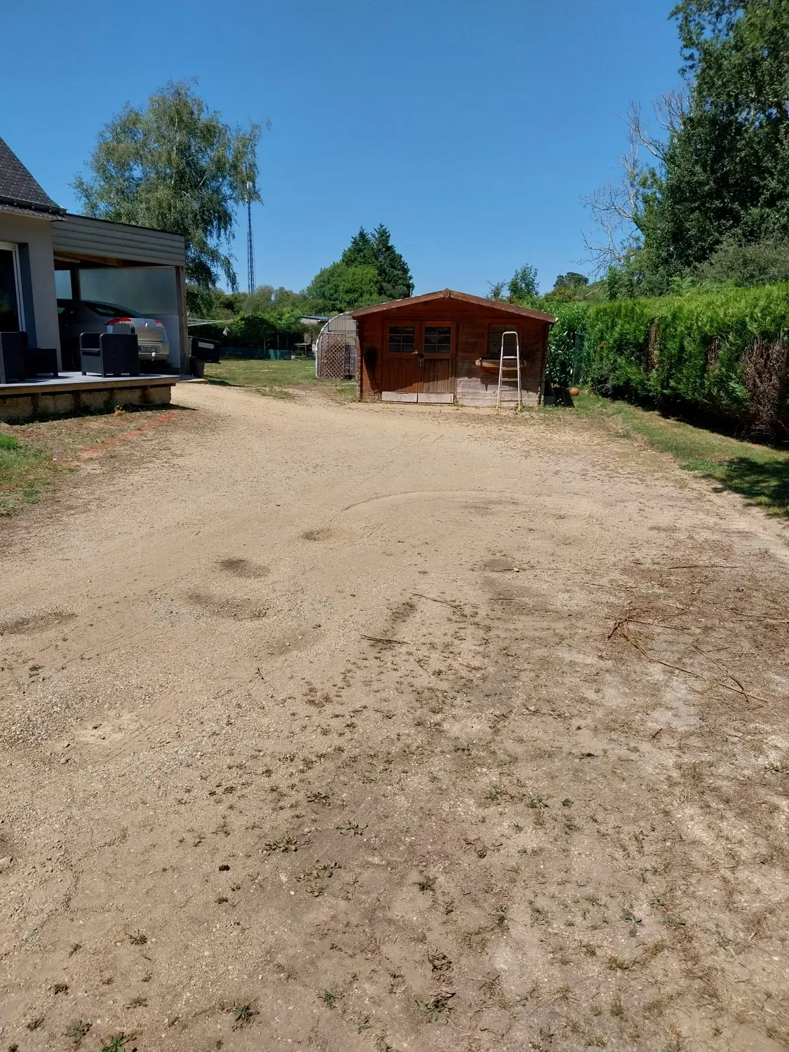 Cour en sable stabilisé avant enrobé, cabanon en arrière-plan (avant)