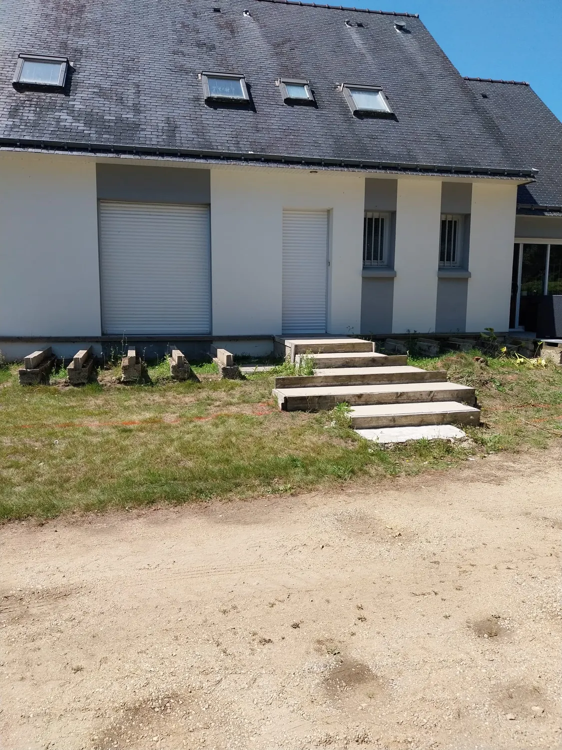 Façade de maison avec escalier et sol en sable avant enrobé (avant)