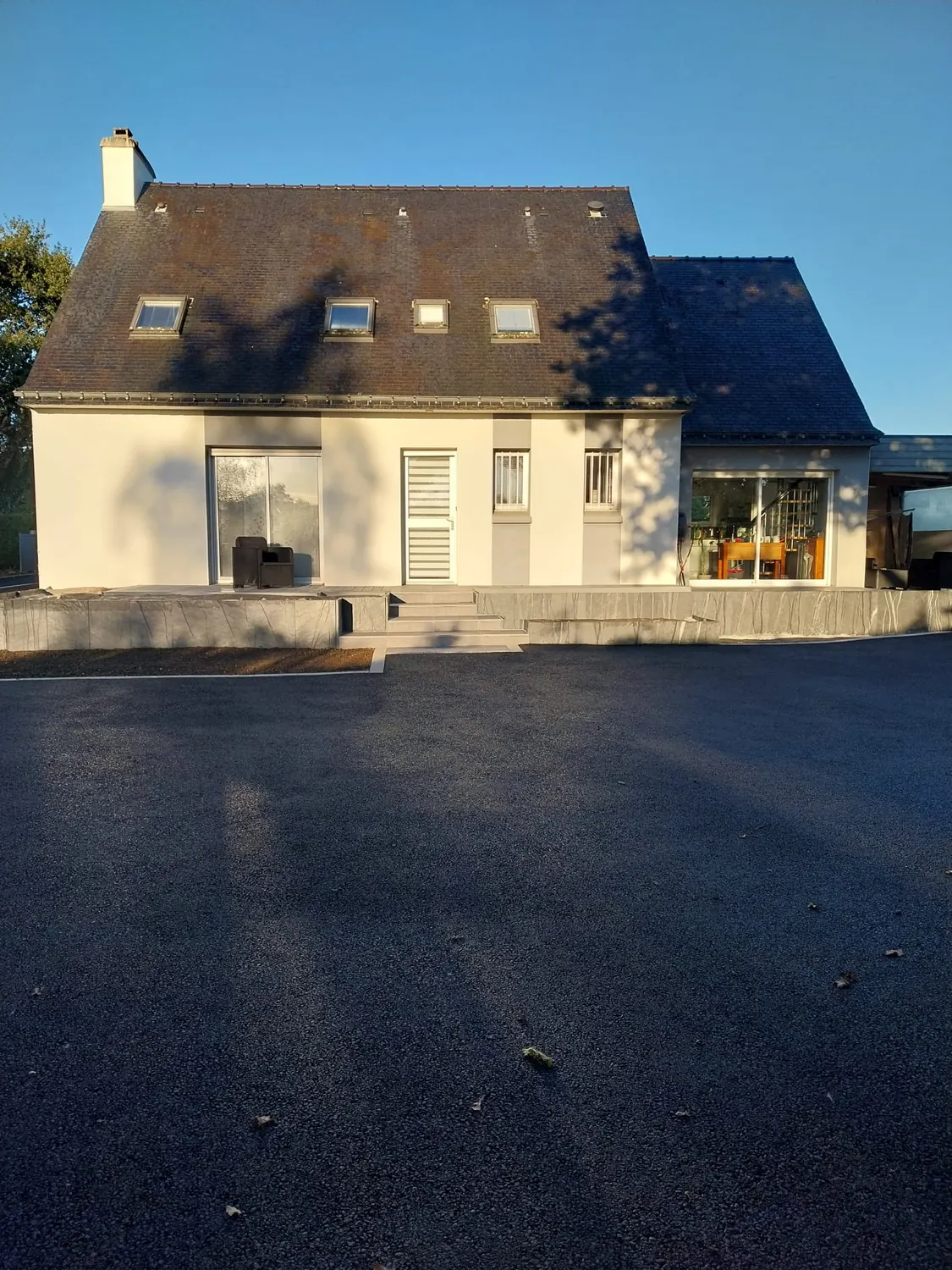 Cour en enrobé neuf devant la façade d'une maison à escalier (après)