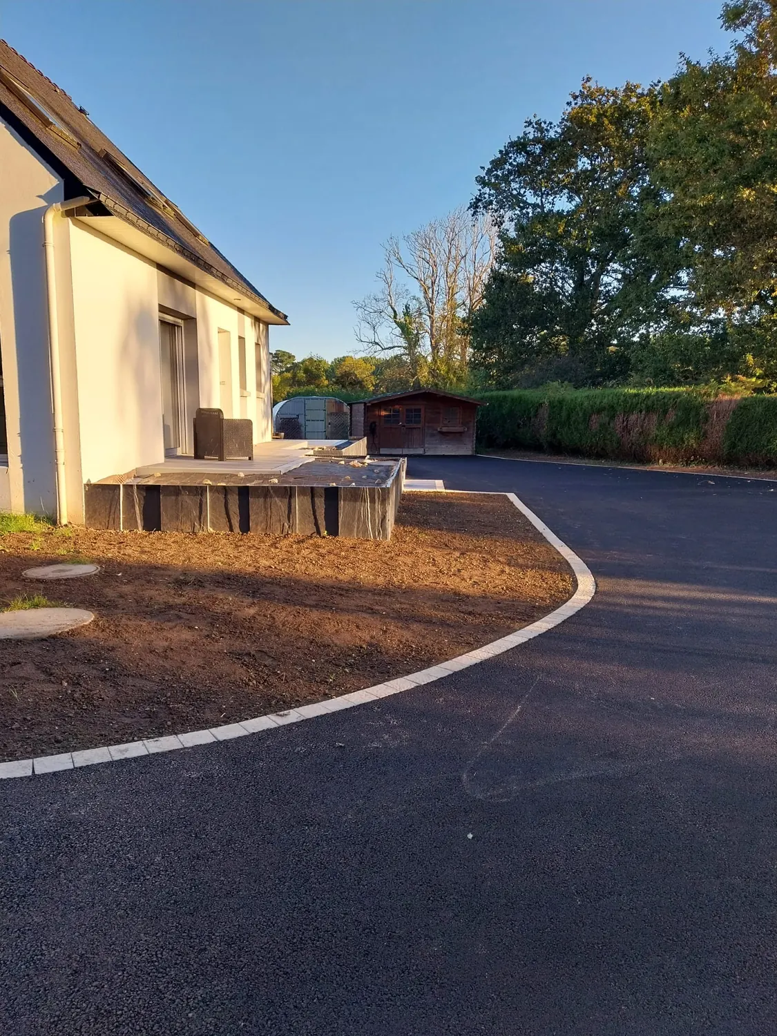Allée en enrobé courbe bordée de béton blanc autour d'une maison (après)