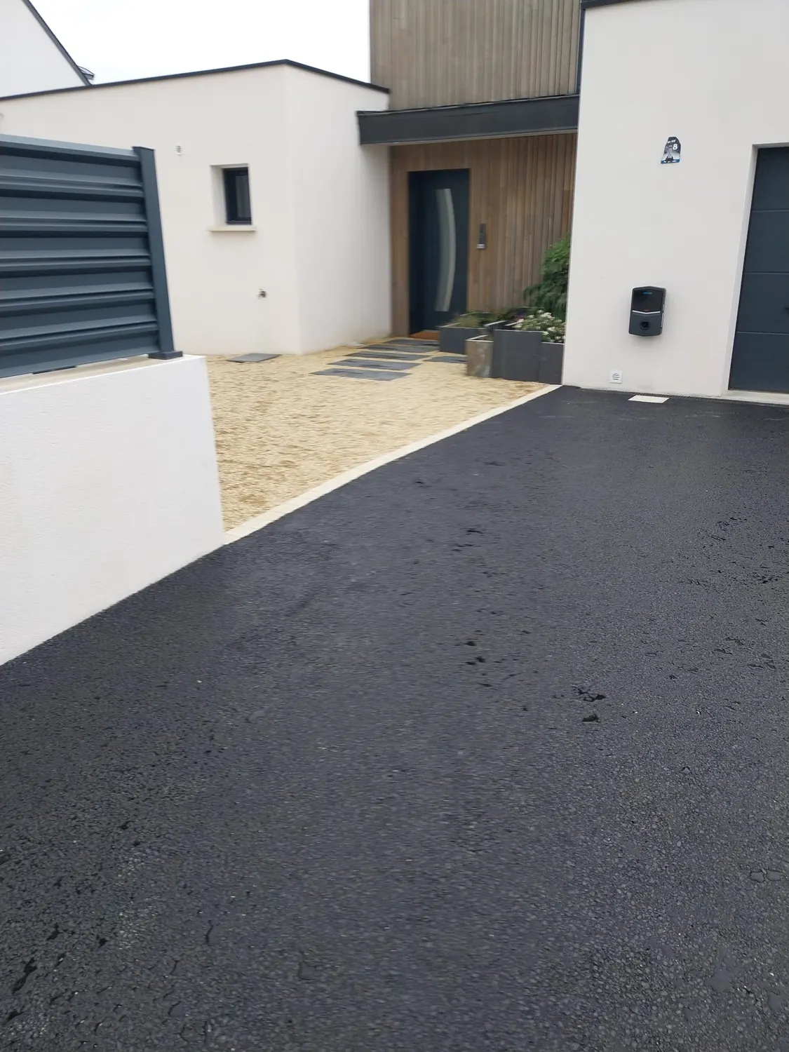 Enrobé neuf au pied d'une entrée en bois avec gravier décoratif