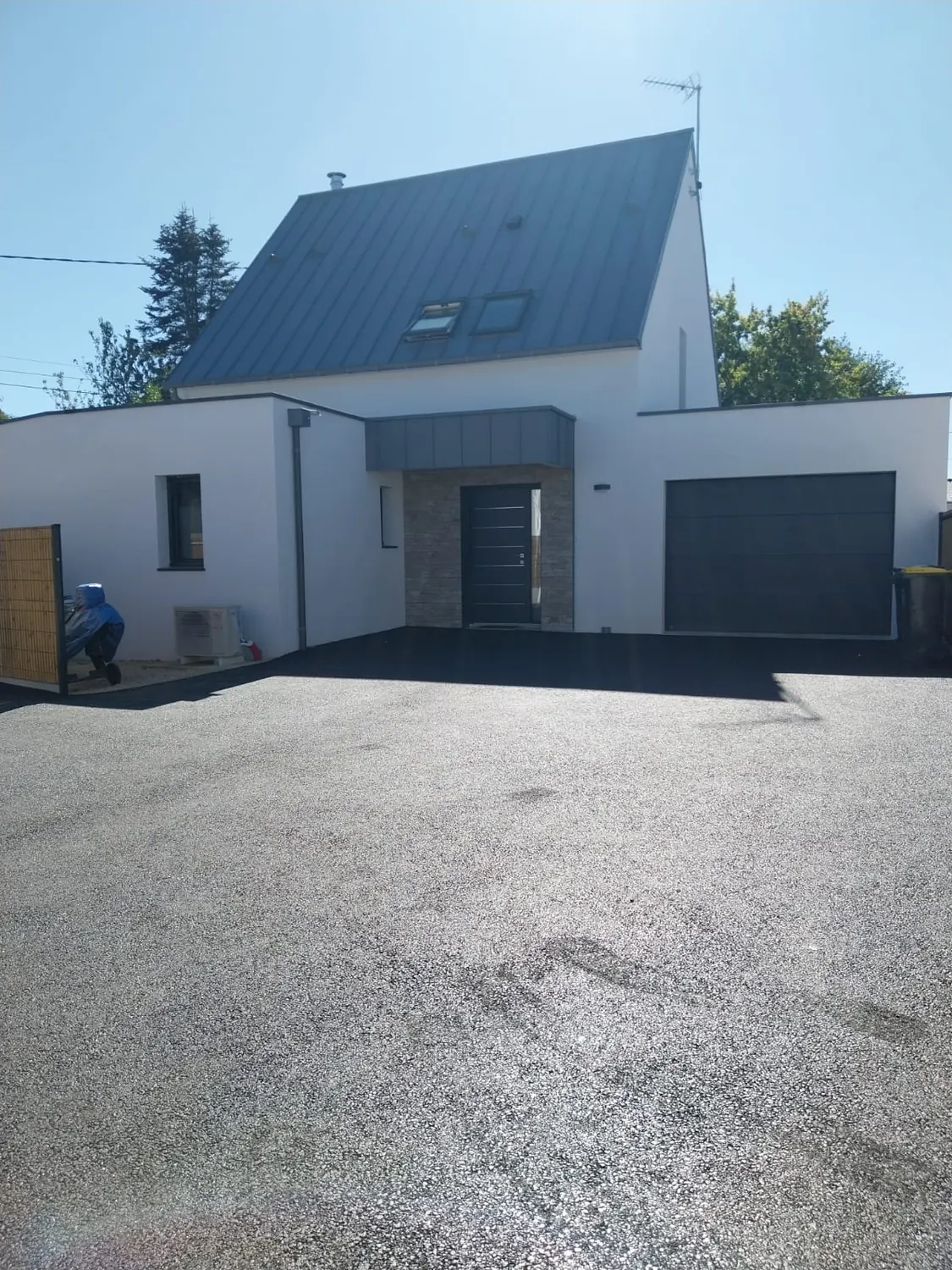 Allée et parking en enrobé noir devant une maison neuve avec garage
