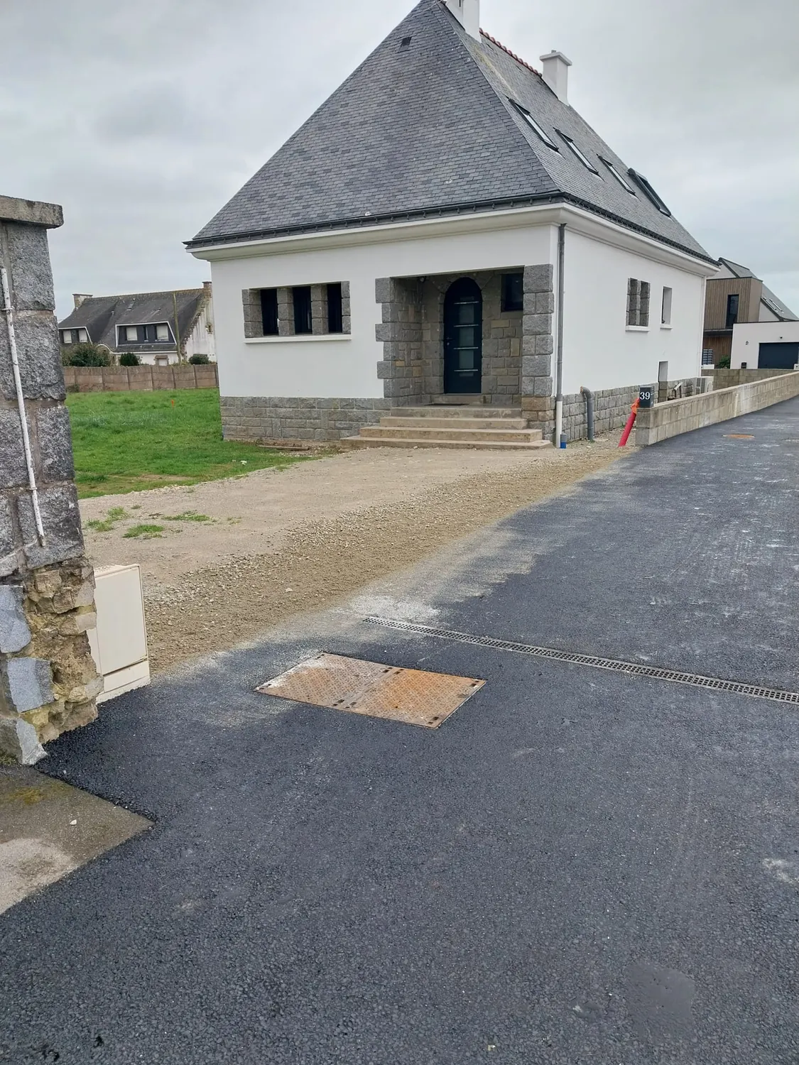 Enrobé et tampon de regard en fonte devant une maison en pierre
