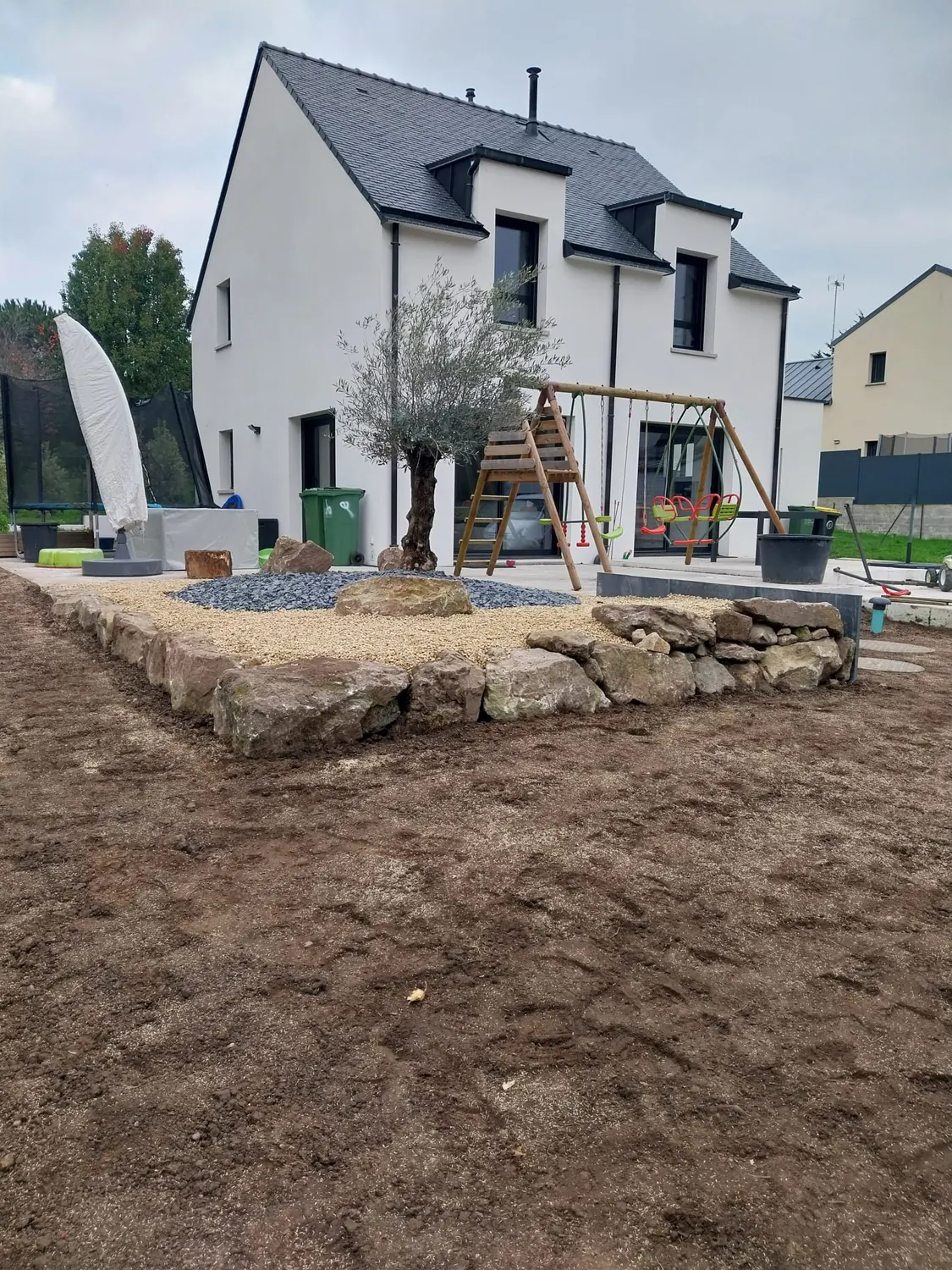 Massif en pierres devant une maison neuve, pelouse en préparation