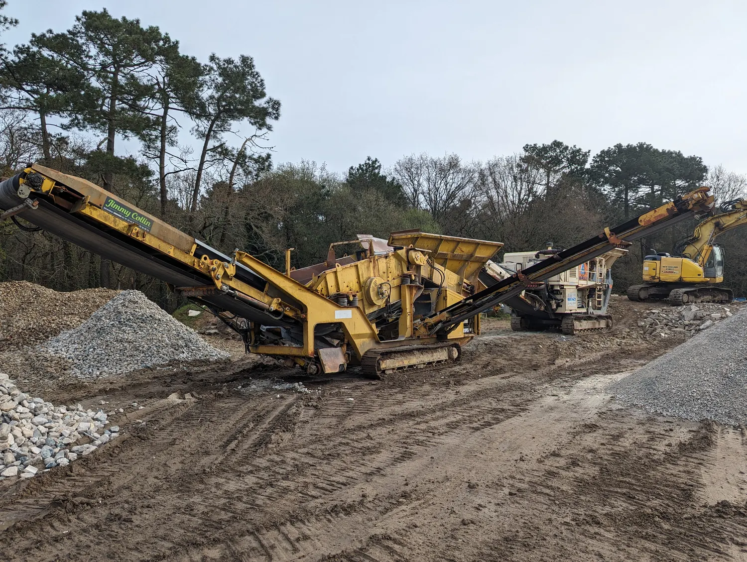 Crible mobile sur chenilles et tas de matériaux recyclés criblés