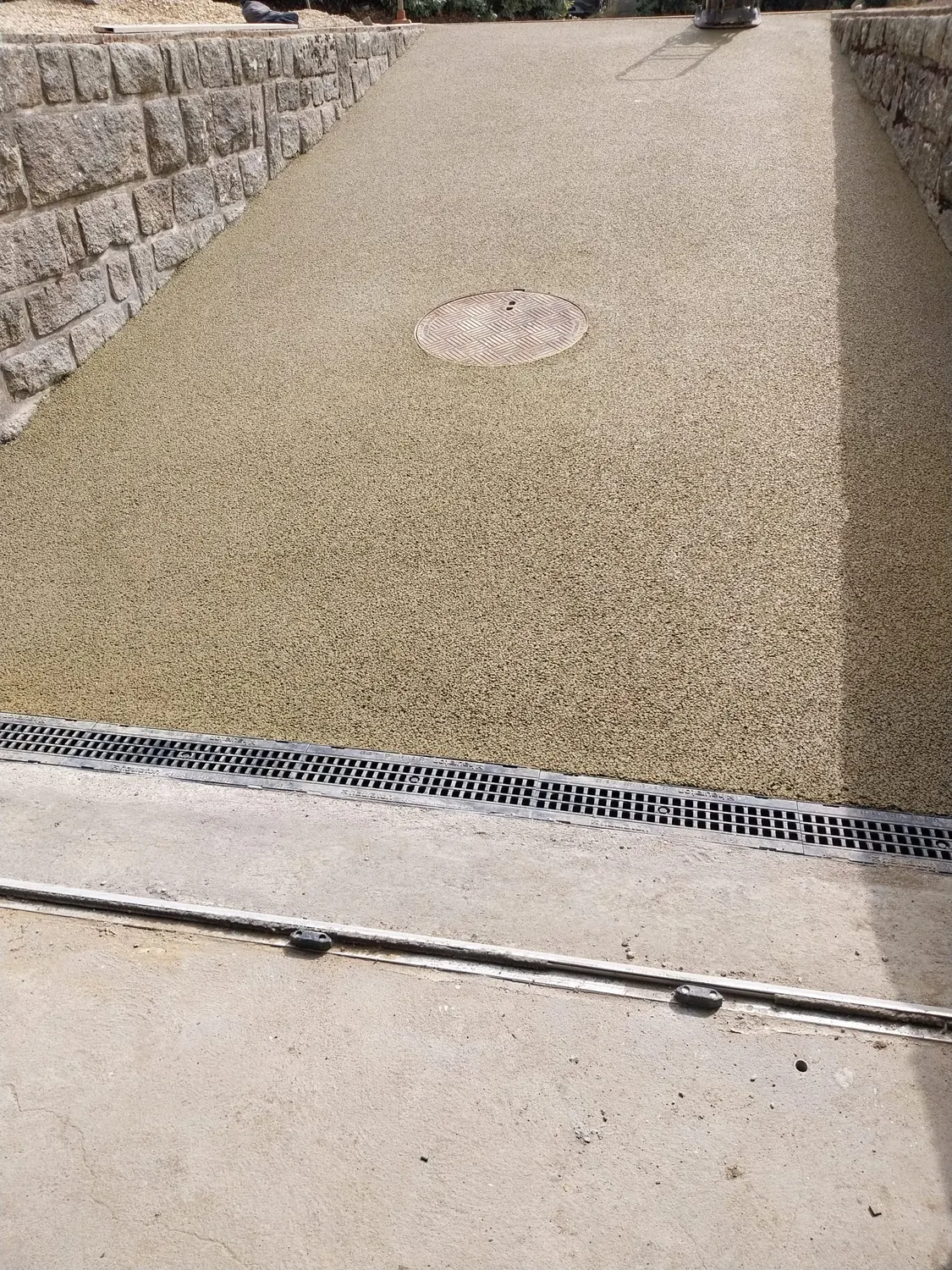 Sol en résine drainante avec regard rond et caniveau à grille