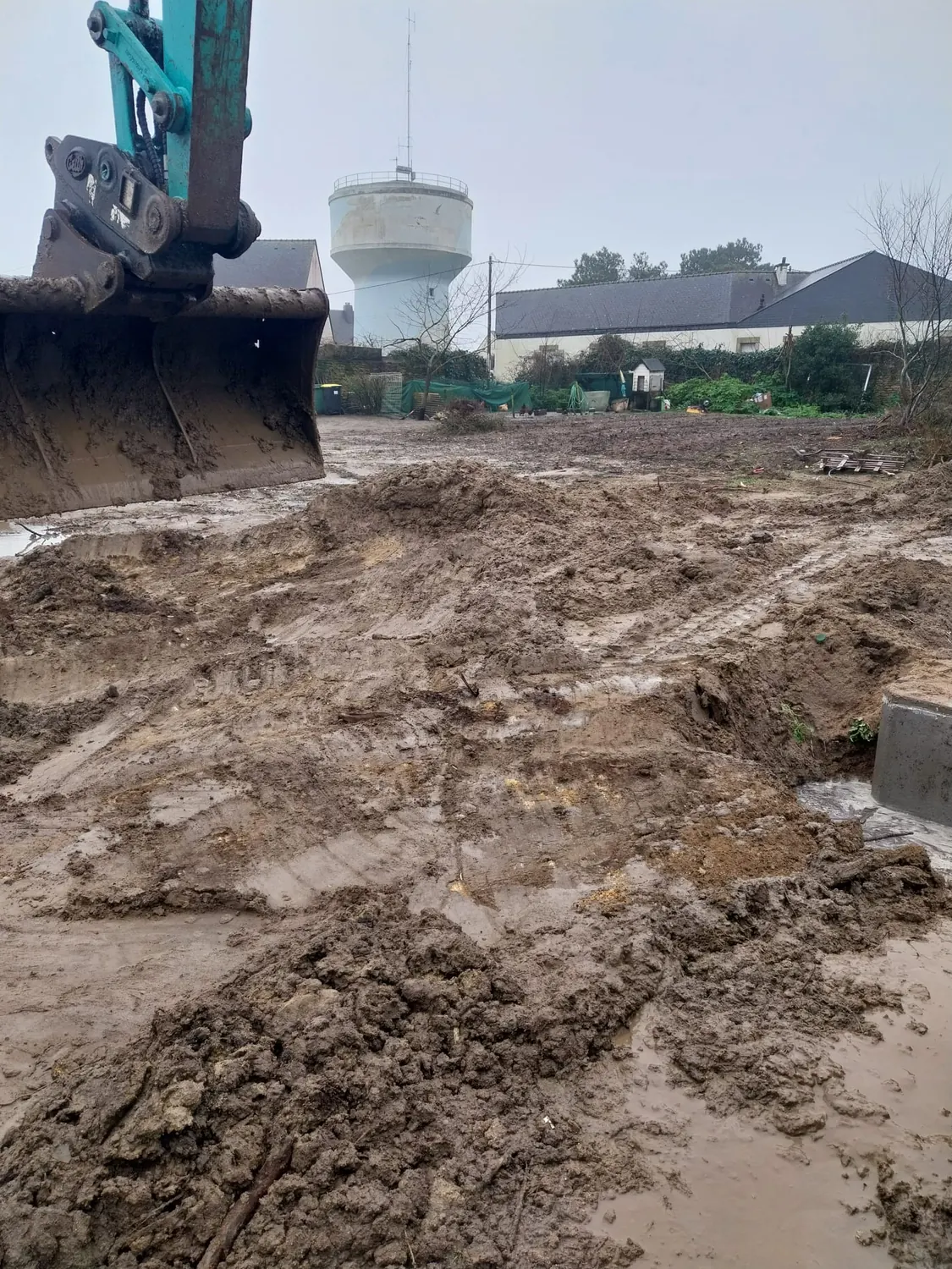 Godet de pelle sur un chantier de terrassement, château d'eau au loin