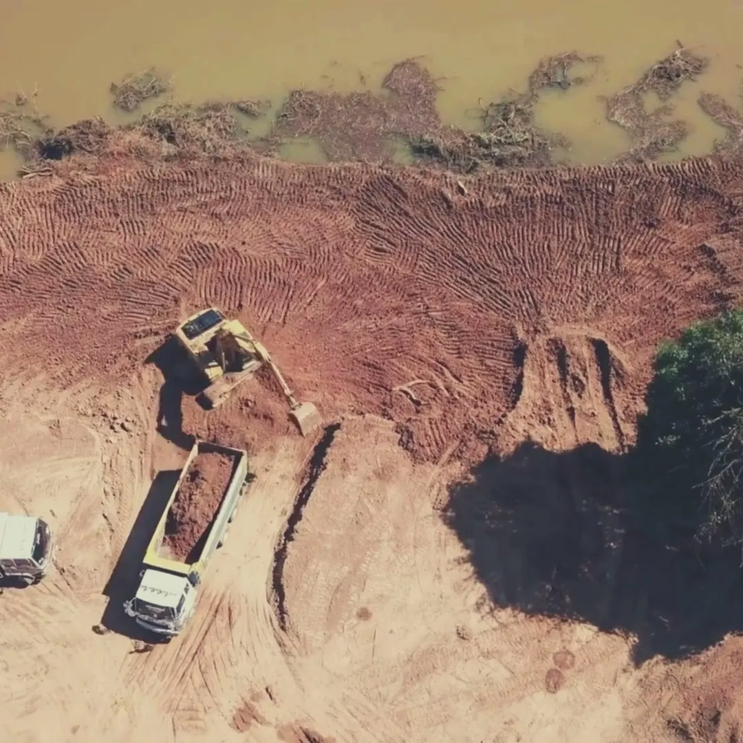 Vue aérienne d'un chantier de terrassement : pelle et camions benne