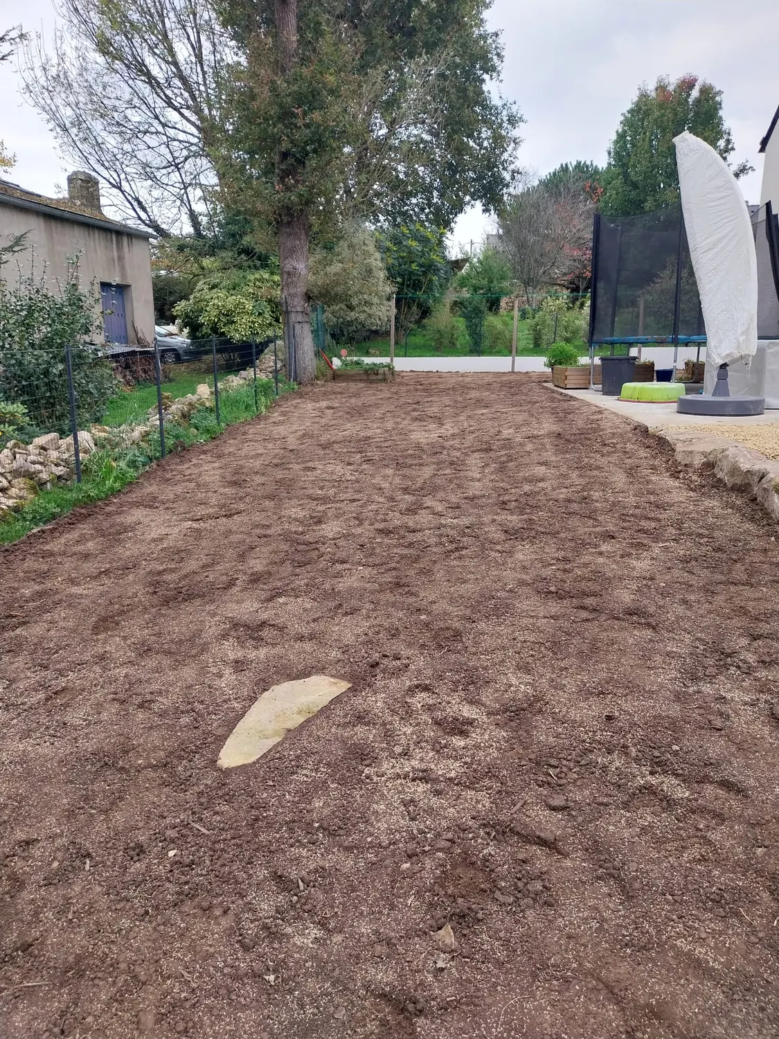 Terre préparée le long d'un jardin avec bordure béton