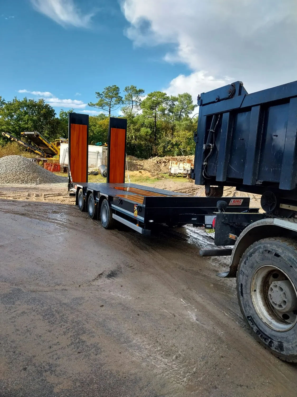 Semi-remorque porte-engin et camion benne sur un chantier
